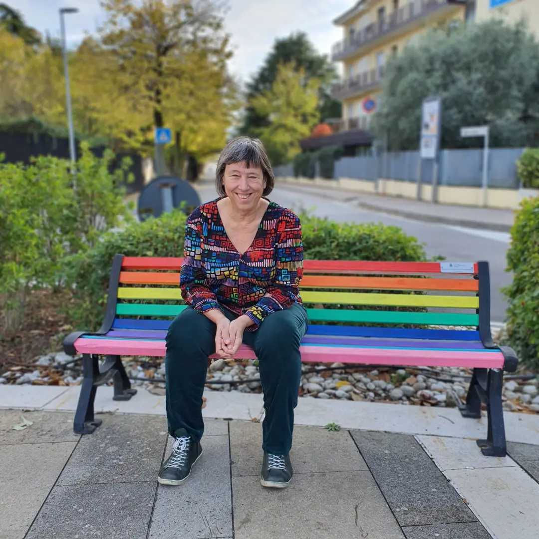 Coach Marion Jakumeit sitzt auf einer regenbogen Bank